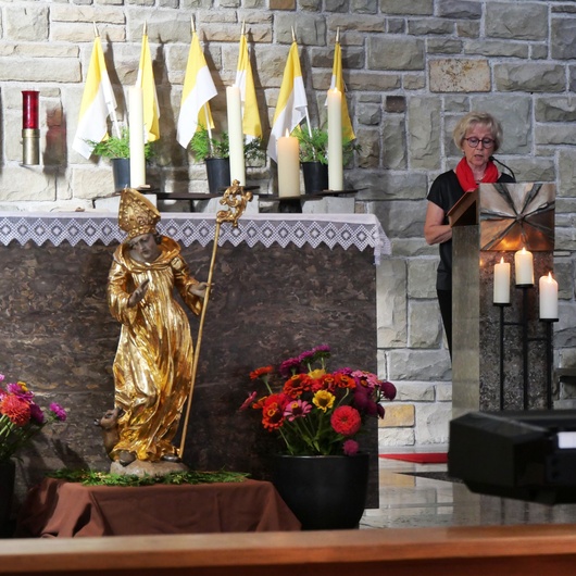 Blick in den Chorraum. Man sieht die Figur des heiligen Ägidius vor dem Altar und hinten rechts die Lektorin am Ambo.