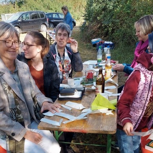 An einem Biertisch im Freien sitzen Menschen beieinander