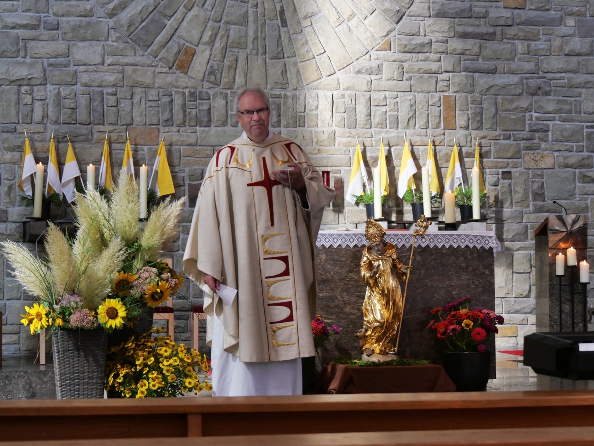 Der Pfarrer predigt im Gottesdienst. Er ist dazu nach vorn vor den Altar zur Figur des Kirchenpatrons gekommen.